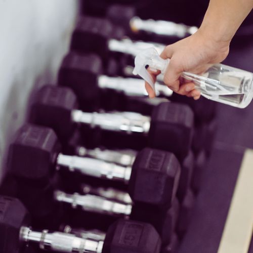 Janitorial staff sanitizing gym equipment at a fitness center